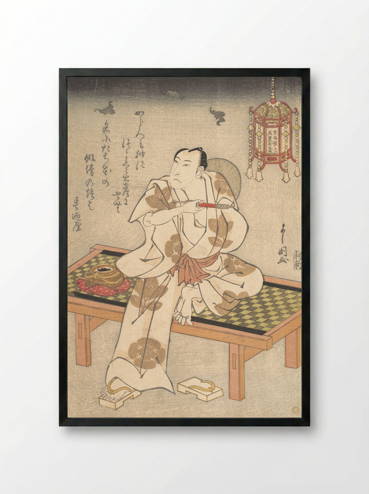 An Actor of the Ichimura Line Sitting on a Shogi (Wooden Bench) and Holding a Pipe - Ippyotei Yoshikuni - Framed Print Black