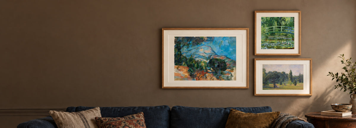 Living room wall with framed prints of Cézanne's Mont Sainte-Victoire, Monet's Japanese Bridge and Pissarro's Gardens at Kew above a navy sofa